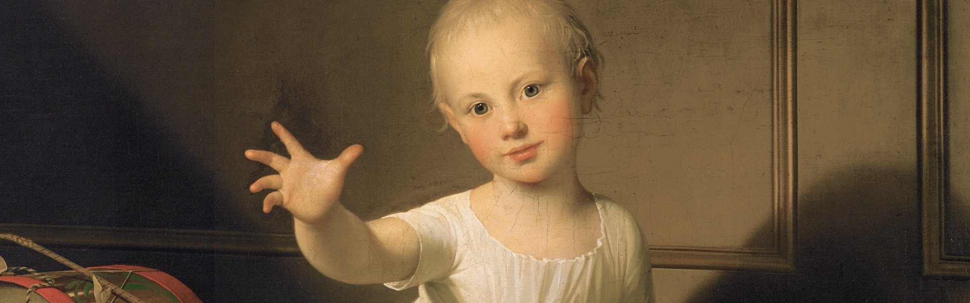 Das Gemälde „Herzog Friedrich Emil August von Schleswig-Holstein-Sonderborg-Augustenburg, gen. Prinz von Noer“ von Jens Juel zeigt einen kleinen Jungen. Er trägt ein weißes Gewand und streckt seine Hand den Betrachtenden entgegen. Neben ihm befindet sich Spielzeug, eine Trommel und ein Holzpferd.. 