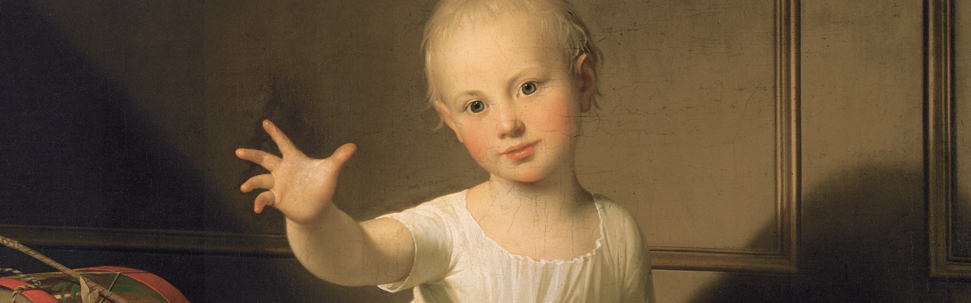 Das Gemälde „Herzog Friedrich Emil August von Schleswig-Holstein-Sonderborg-Augustenburg, gen. Prinz von Noer“ von Jens Juel zeigt einen kleinen Jungen. Er trägt ein weißes Gewand und streckt seine Hand den Betrachtenden entgegen. Neben ihm befindet sich Spielzeug, eine Trommel und ein Holzpferd.. 