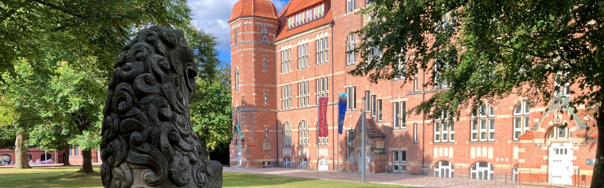 Eine Steinfigur steht vor einem alten Gebäude. 