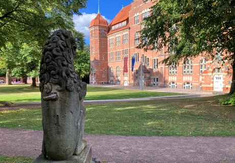 Eine Steinfigur steht vor einem alten Gebäude. 