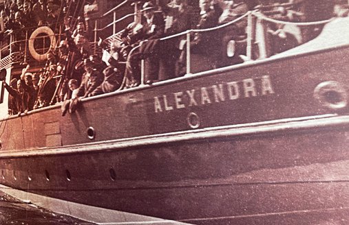 Billedet viser et gammelt fotografi af salondampskibet ALEXANDRA. Det er et detaljeret billede. Man kan se mange mennesker, der kigger ud over rælingen. Der er næsten ingen ledige pladser at se.