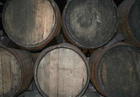 Im Keller des Flensburger Schifffahrtsmuseums liegen Rumfässer fein aufgestapelt. Hier ist eine Nahaufnahme von der Installation zu sehen. Man sieht sechs Fässer, die auf der Seite liegen, sodass nur ihre Böden zu sehen sind.