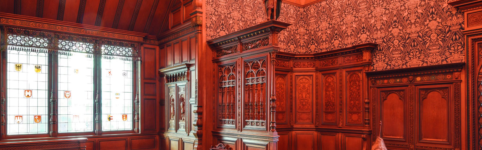 I et rum med mørkt træ på væggene står et bord med stole.