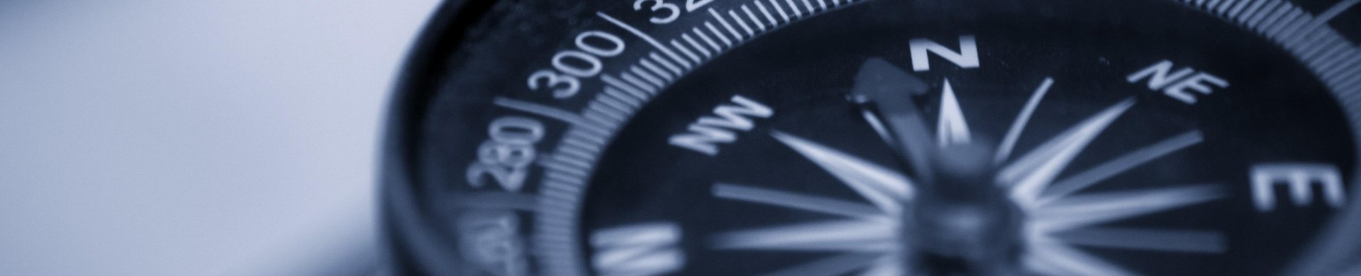 Auf dem foto ist ein moderner Kompass zu sehen. Er zeigt Richtung Norden. Der Hintergrund ist verschwommen.