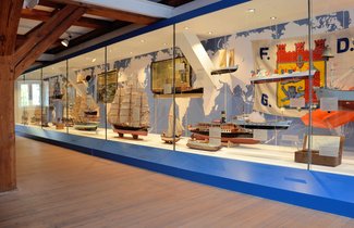 In der Ausstellung HAFEN & HÖFE gibt es eine ganz große Vitrine, die sich einmal über die gesamte Breite des Raumes zieht. In der Vitrine sind verschiedene Flensburger Schiffe zu sehen.