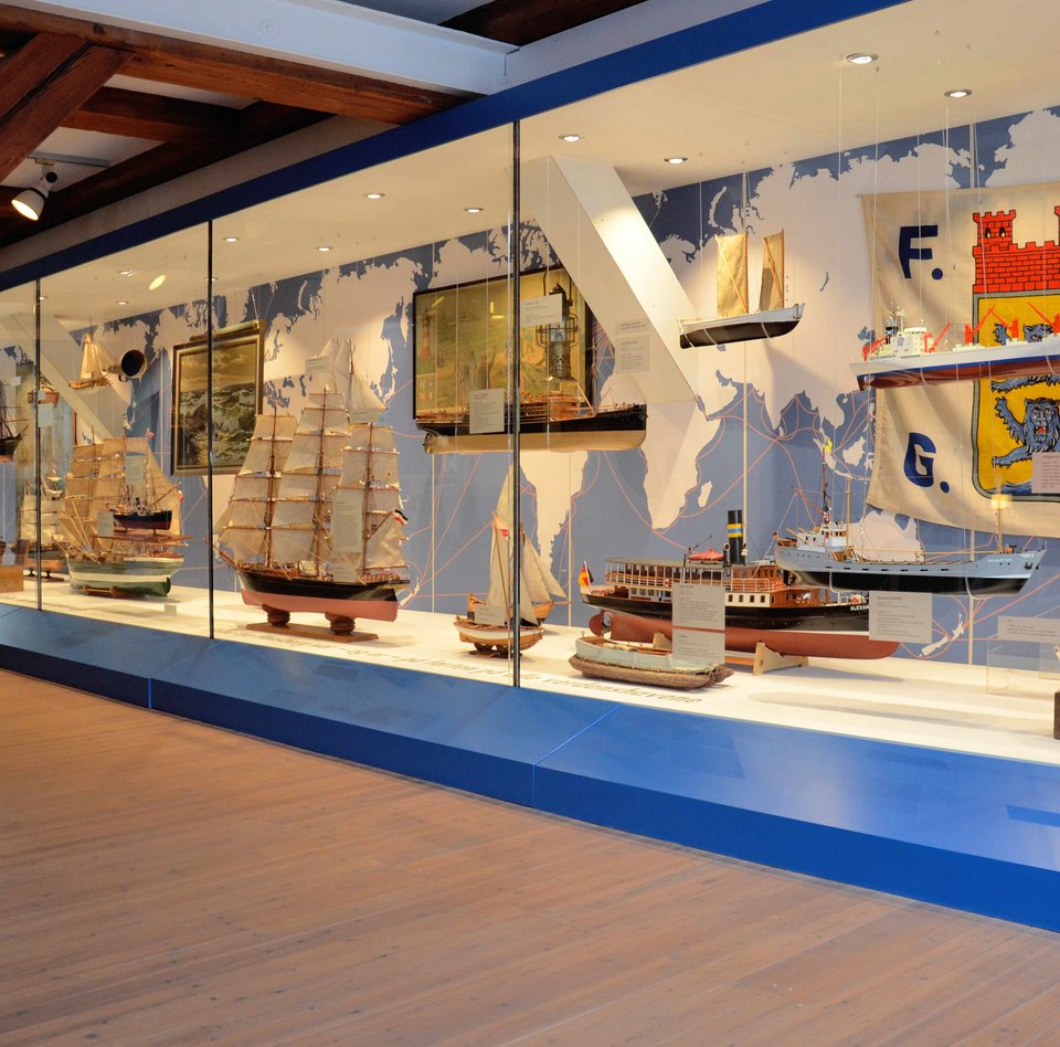 In der Ausstellung HAFEN & HÖFE gibt es eine ganz große Vitrine, die sich einmal über die gesamte Breite des Raumes zieht. In der Vitrine sind verschiedene Flensburger Schiffe zu sehen.
