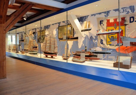 In der Ausstellung HAFEN & HÖFE gibt es eine ganz große Vitrine, die sich einmal über die gesamte Breite des Raumes zieht. In der Vitrine sind verschiedene Flensburger Schiffe zu sehen.