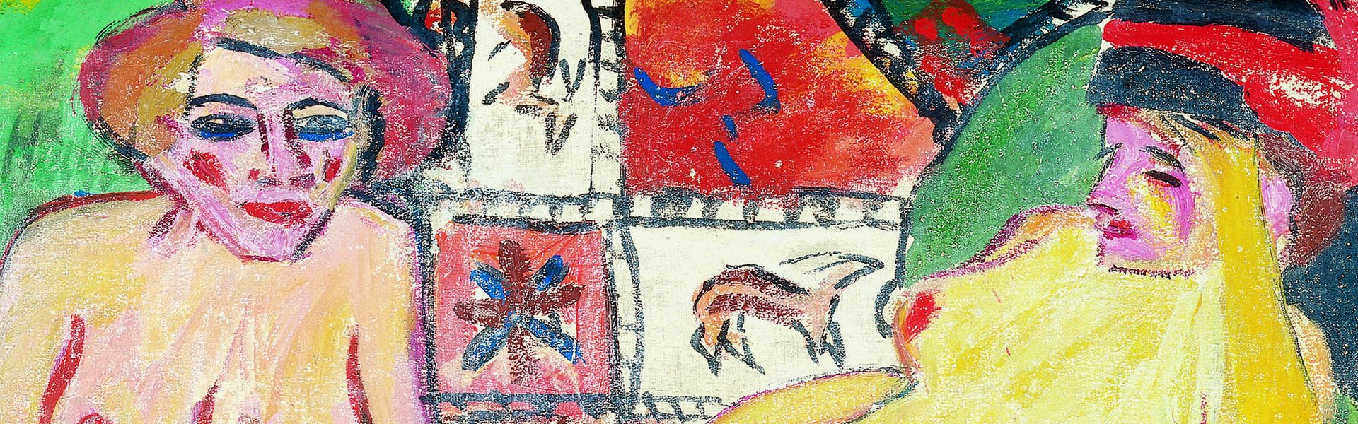 Zwei nackte Frauen sitzen und liegen auf einem Sofa. Im Hintergrund ist ein Teppich mit Tieren an der Wand. Vorne steht ein Tisch mit Früchten.