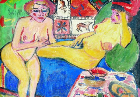 Zwei nackte Frauen sitzen und liegen auf einem Sofa. Im Hintergrund ist ein Teppich mit Tieren an der Wand. Vorne steht ein Tisch mit Früchten.