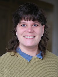 Portrait einer jungen Frau mit schwarzen Haaren. Sie lächelt in die Kamera. 