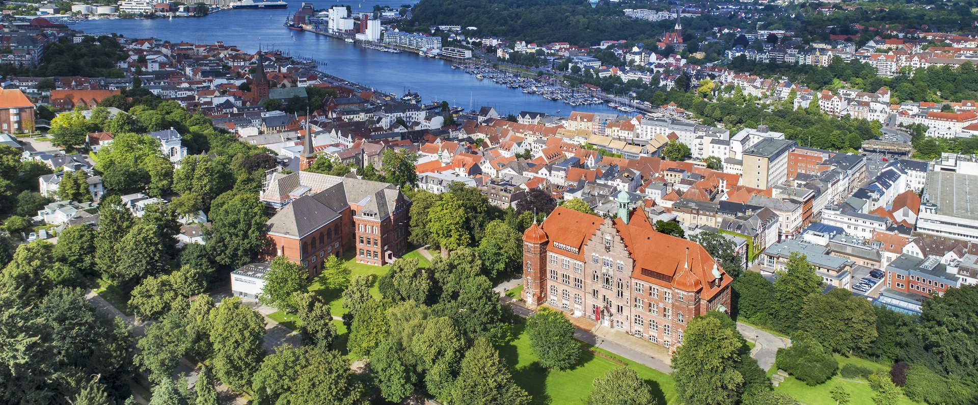 Das Heinrich-Sauermann-Haus und das Hans-Christiansen-Haus sind die beiden großen Häuser vorne. Zusammen sind sie der Museumsberg Flensburg. Das Foto wurde von weit oben gemacht, deshalb sind noch andere Häuser und die Flensburger Förde zu sehen. 