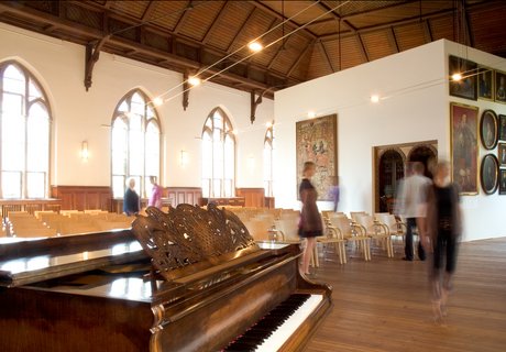 In der Aula des Museumsberg Flensburg finden verschiedene Veranstaltungen statt. Im Vordergrund steht ein Klavier, das für Konzerte genutzt wird. Dahinter sind viele Stühle für die Gäste zu sehen.