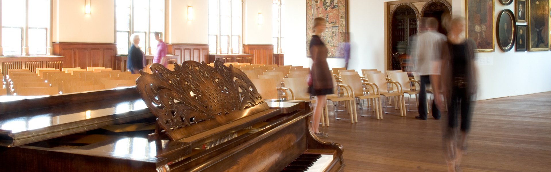 In der Aula des Museumsberg Flensburg finden verschiedene Veranstaltungen statt. Im Vordergrund steht ein Klavier, das für Konzerte genutzt wird. Dahinter sind viele Stühle für die Gäste zu sehen.