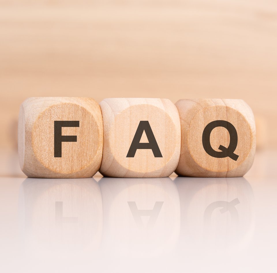 Detailaufnahme von drei Holzwürfel, auf denen die Buchstaben F, A und Q stehen. Der helle Hintergrund ist verschwommen. Dort können weitere Würfel erahnt werden.